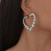 Silver heart-shaped hoop earrings, adding a charming flair to any outfit with their sleek design.